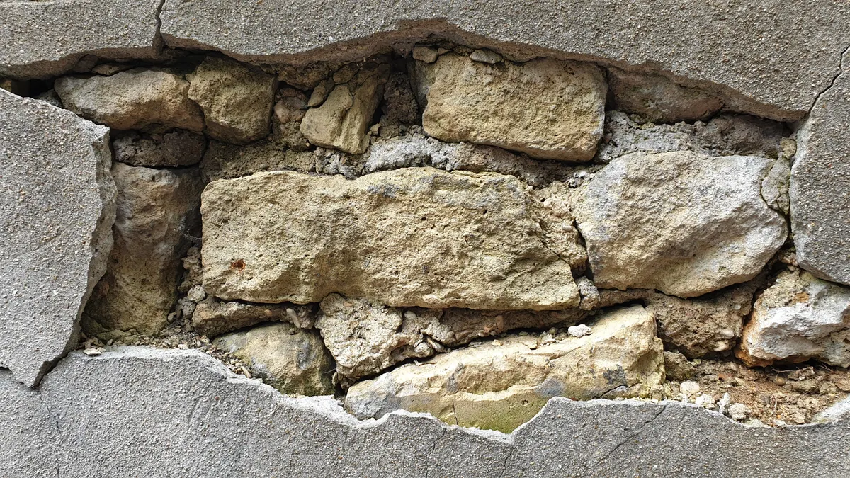 Foundation Movement and Structural Behavior — The Complete Guide Damaged wall with exposed stones and a large gap