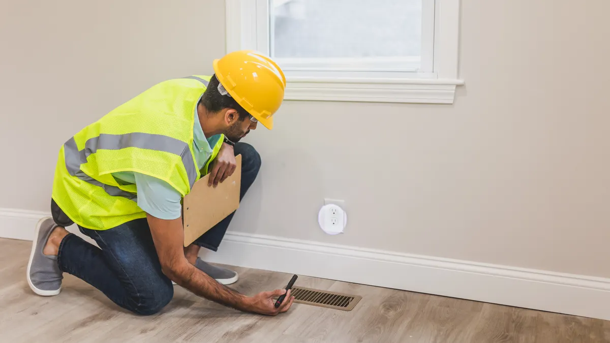 Home inspector checking floor vent with clipboard